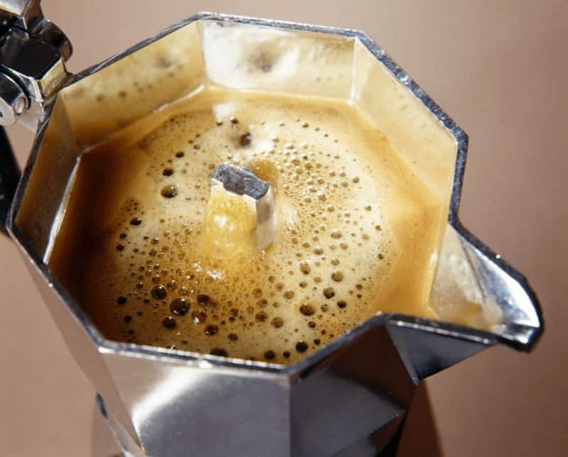 Close up of top compartment of moka pot brewing coffee.