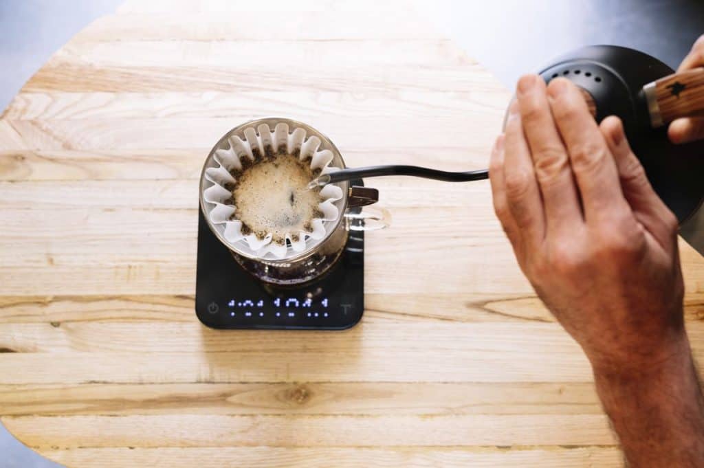 Home barista preparing coffee with pour over filter and coffee weighing scales