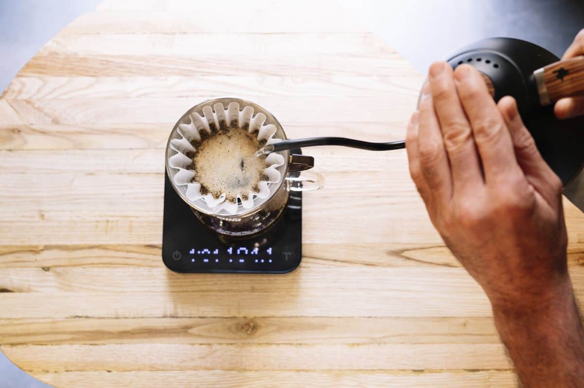 Home barista preparing coffee with pour over filter and coffee weighing scales
