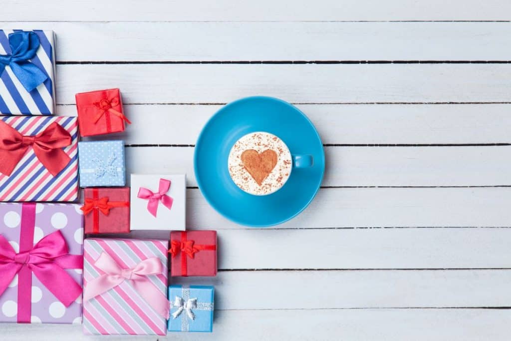 Cappuccino on table surrounded by coffee gifts