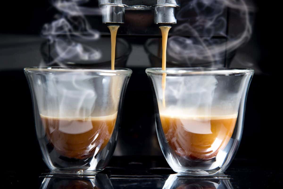 two glass mugs with espresso on automatic coffee machine drip tray