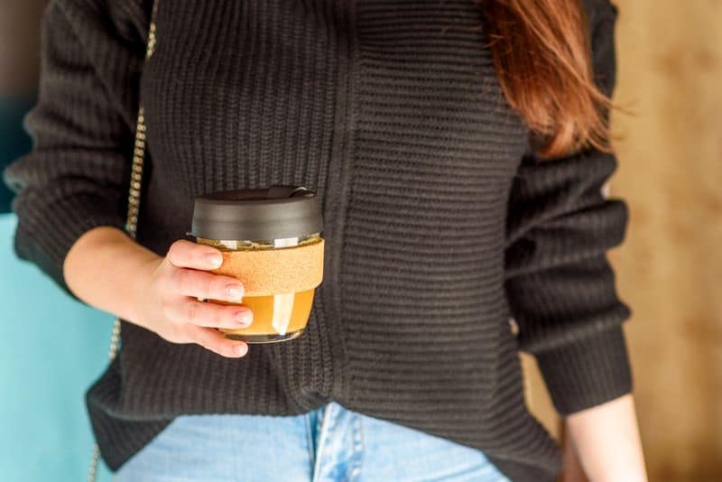 businesswoman holding reusable takeaway glass coffee cup - zero waste