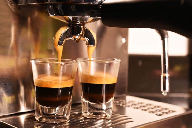Close up of portafilter extracting espresso into glasses