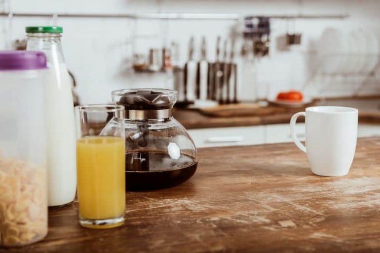 Kitchen bench with glass coffee carafe and coffee mug.
