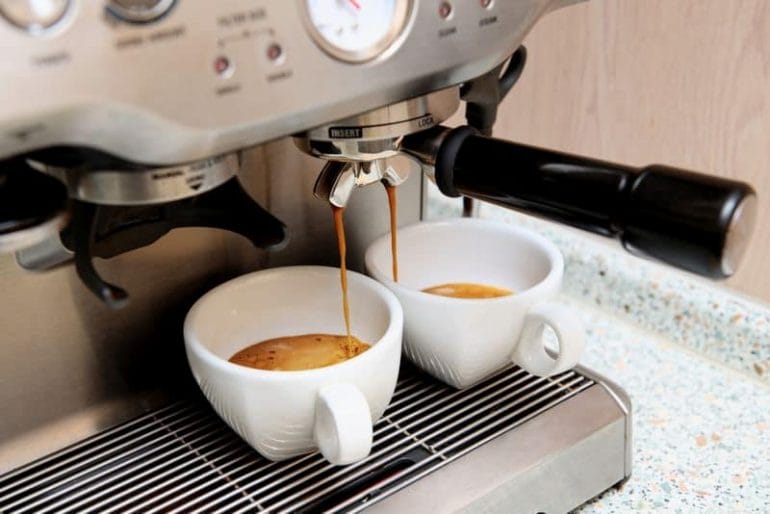 espresso machine extracting espresso into two white coffee cups