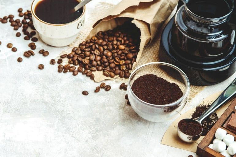 Coffee pot with ground coffee, coffee beans and mug