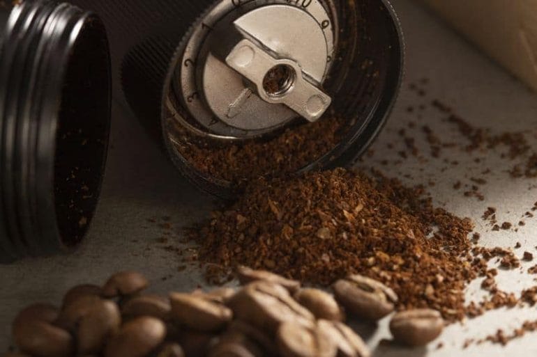 Inside a stepped manual coffee grinder with ground beans