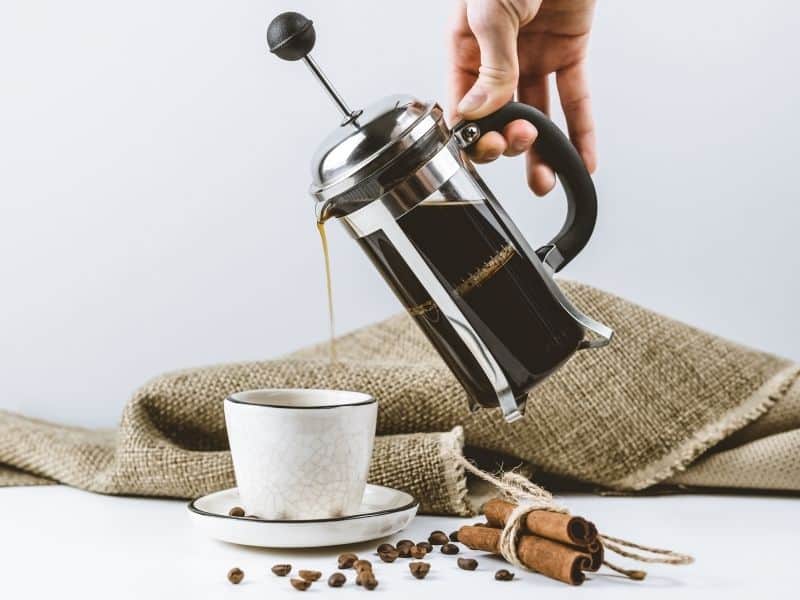 French press coffee maker pouring coffee into cup