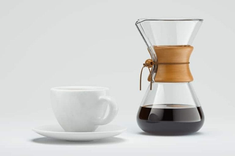 freshly prepared black coffee in chemex pour over coffee maker near white coffee cup