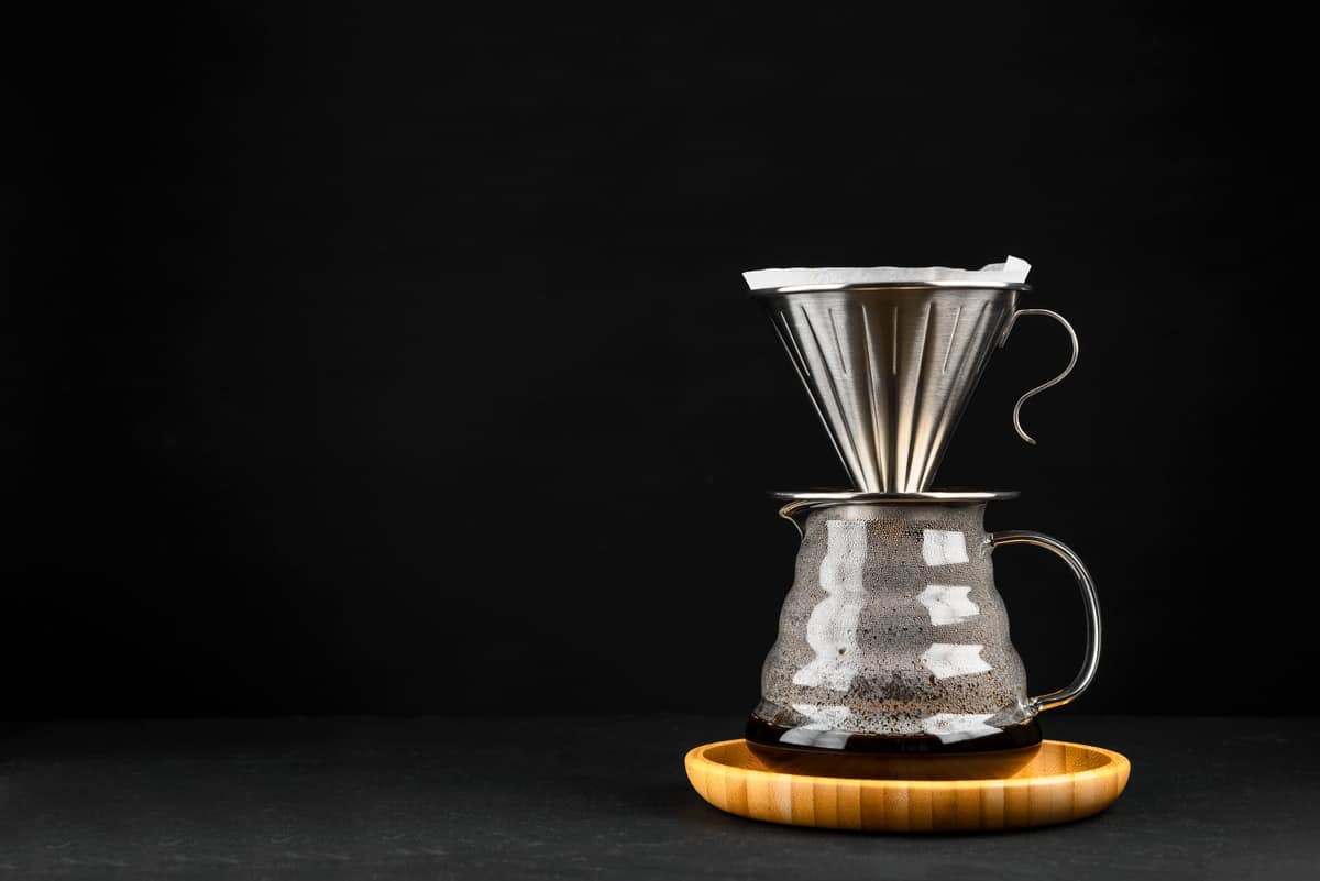 Stainless steel pour over dripper over glass server with freshly brewed coffee.