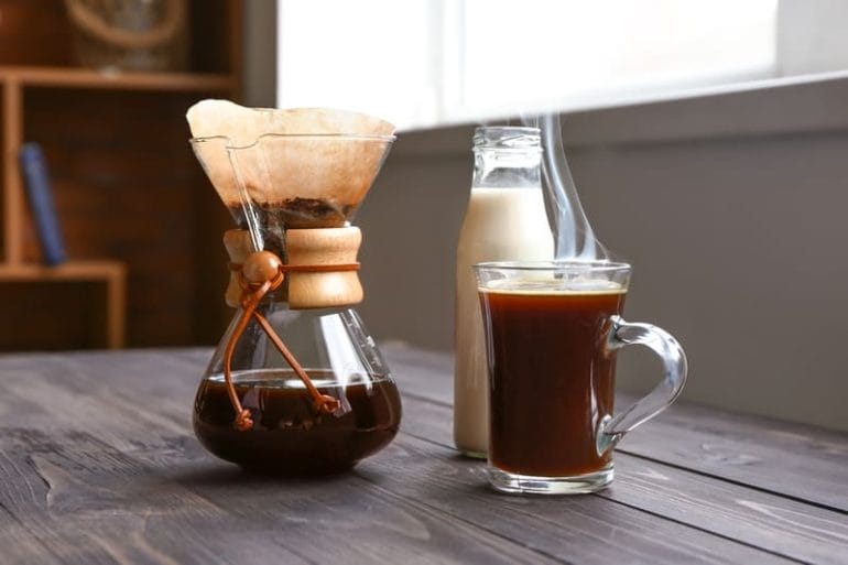 Brewed coffee in chemex and glass with bottle of milk on wooden table