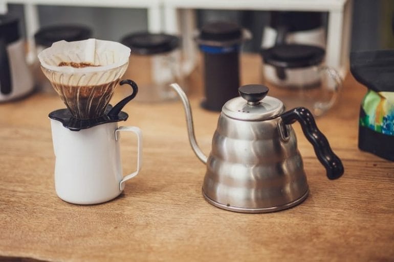 Alternative coffee. Single cup dripper with filter and coffee over the cup and metal kettle.