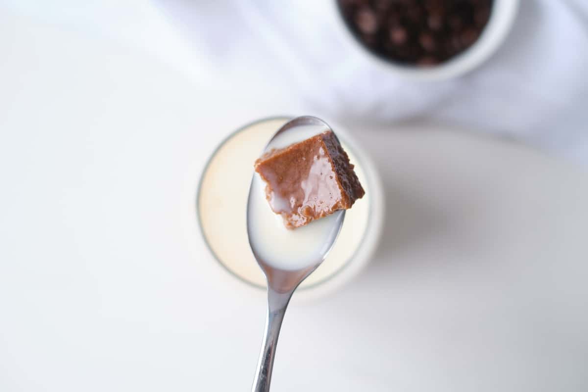 homemade coffee jelly on spoon above glass of milk.