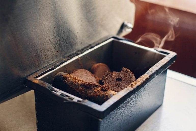 Closeup shot of used hot coffee grounds from espresso machine maker in espresso knock box.