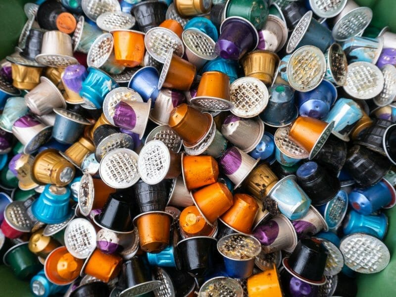 Used coffee capsules rubbish in many different colours in a disposal waste container.