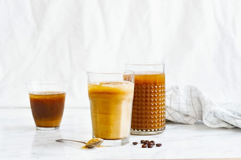 Black iced coffee iced latte and ice coffee with cream in various glasses on white background.