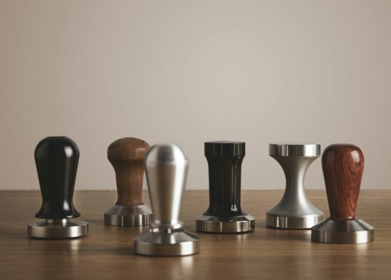 Range of espresso tampers on wooden table. Professional coffee brewing tools.