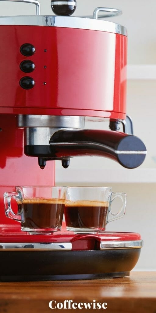 Closeup of small home espresso machine on bench with two glasses of espresso.