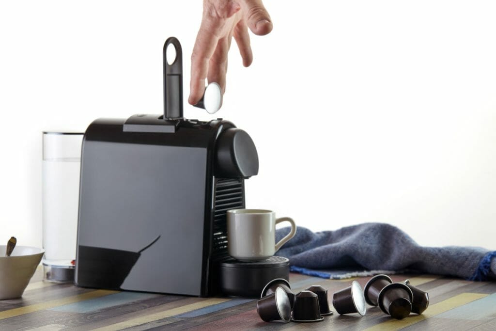 Loading a capsule with ground coffee into a capsule coffee maker.
