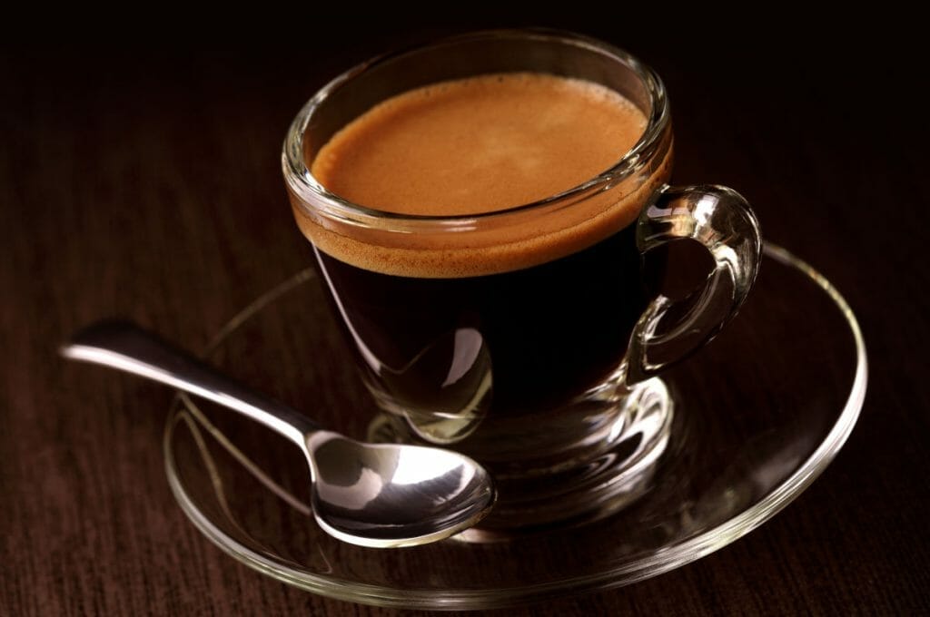 Glass of long black coffee on table.