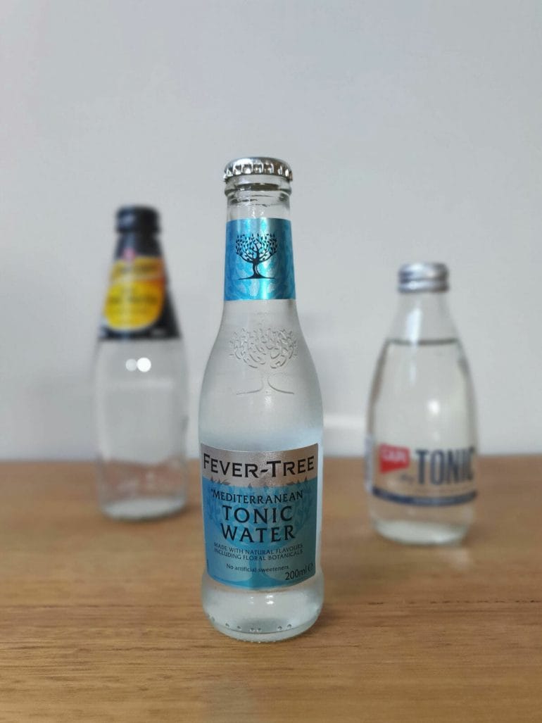 three different types of tonic water in glass bottles.