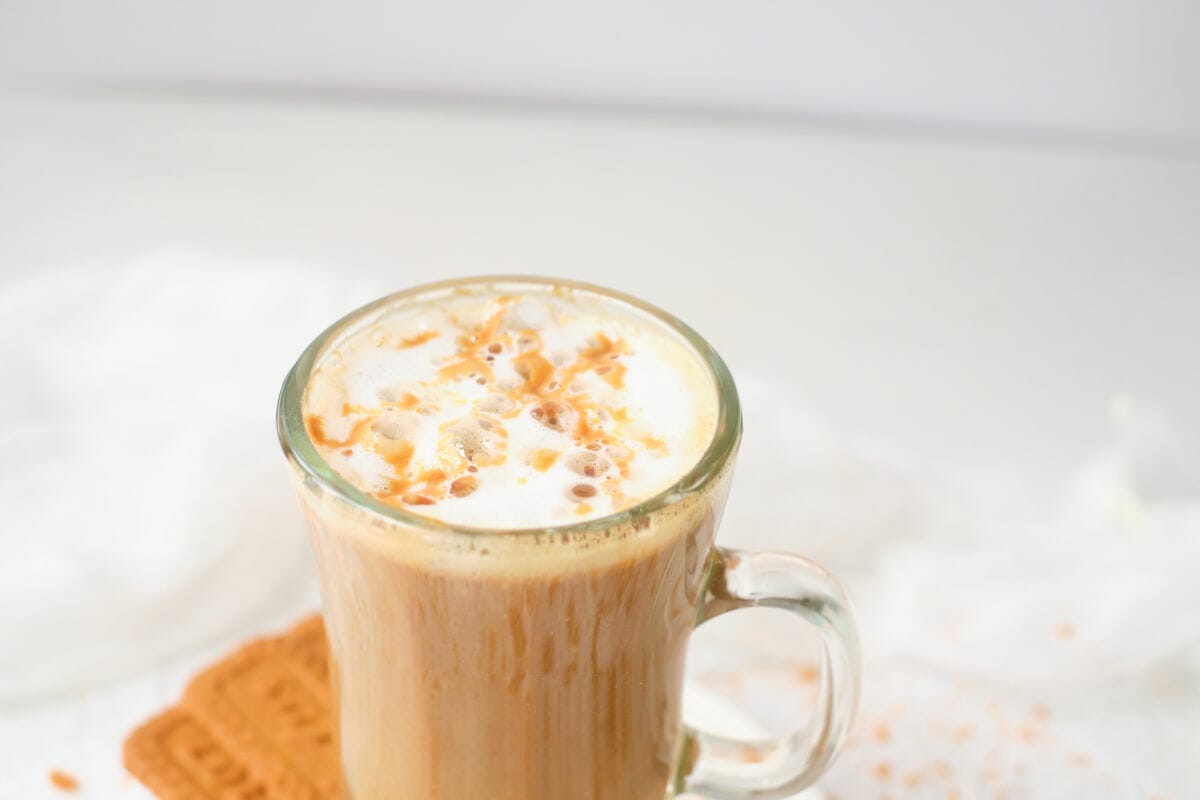 side view of hot latte in mug with cookies on the side.