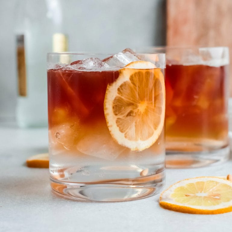 Glass of iced espresso tonic drink with slices of orange.
