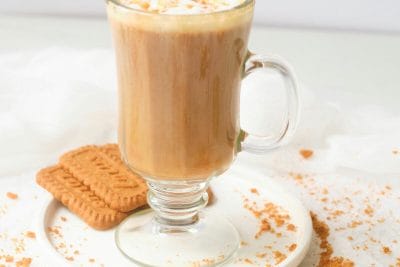 Lotus biscoff latte in glass mug with lotus cookies alongside.