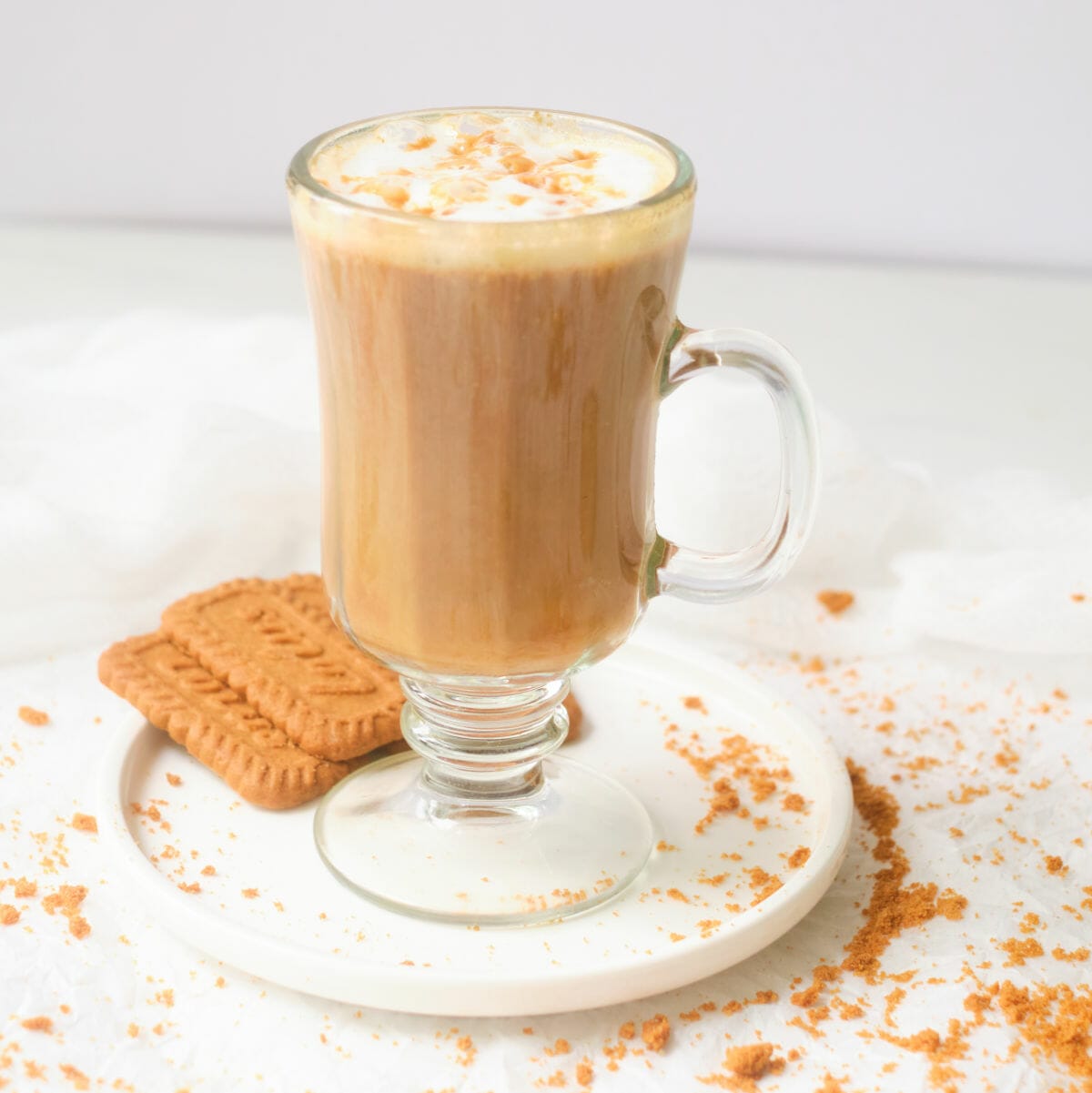 Lotus biscoff latte in glass mug with lotus cookies alongside.
