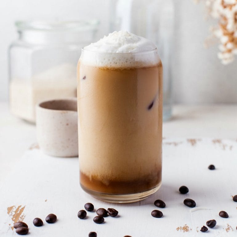iced cold brew with coconut milk in glass with coconut milk foam.