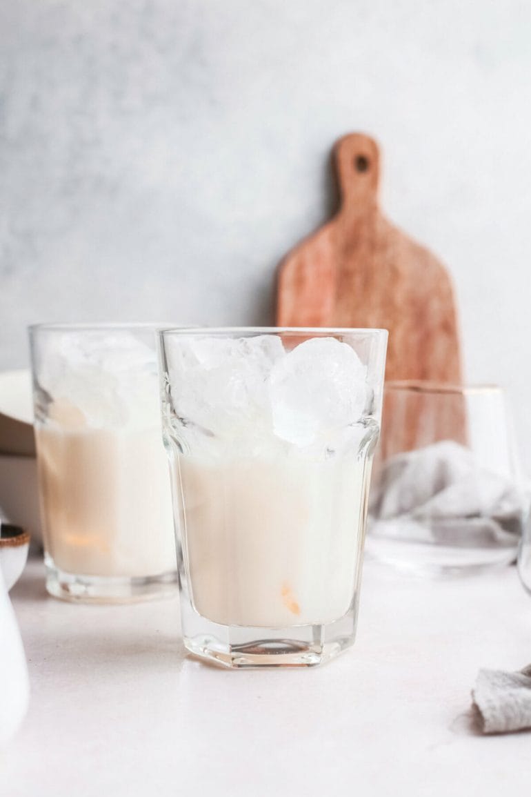 Tall glass filled with ice cubes, water and evaporated milk.