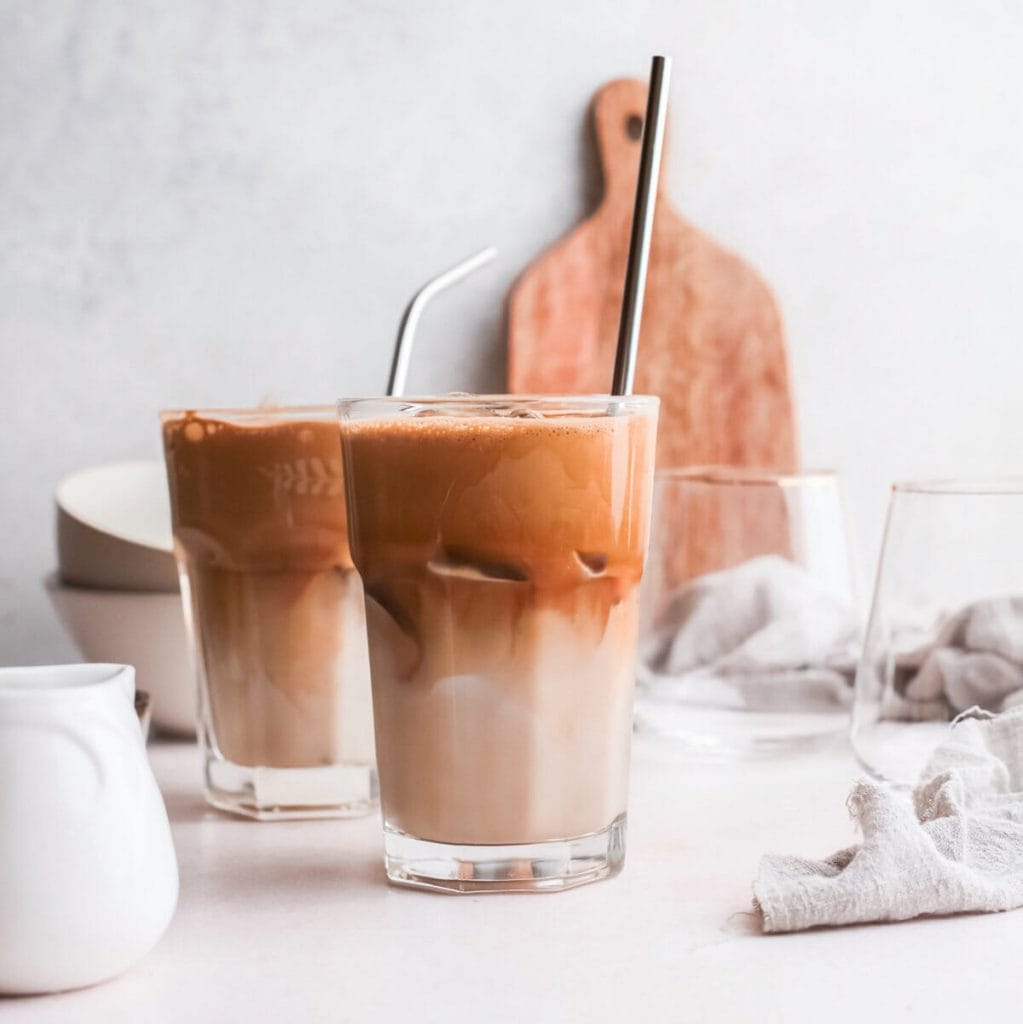 Two glasses of Greek frappe with metal straws.