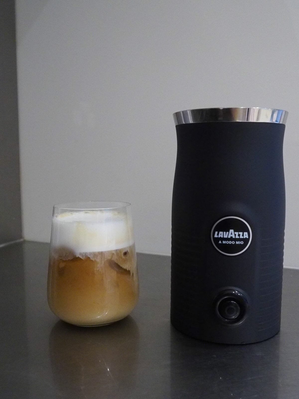 Lavazza automatic milk frother with glass of coffee with cold foam.