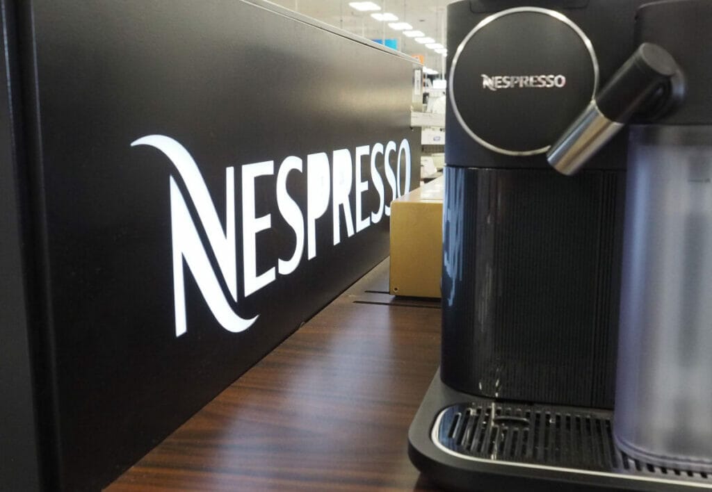Nespresso Pod Coffee Maker with Nespresso Logo alongside.